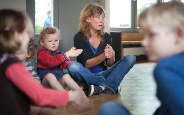 Kleinkinder in einer Spielgruppe mit Leiterin, die Spiele macht