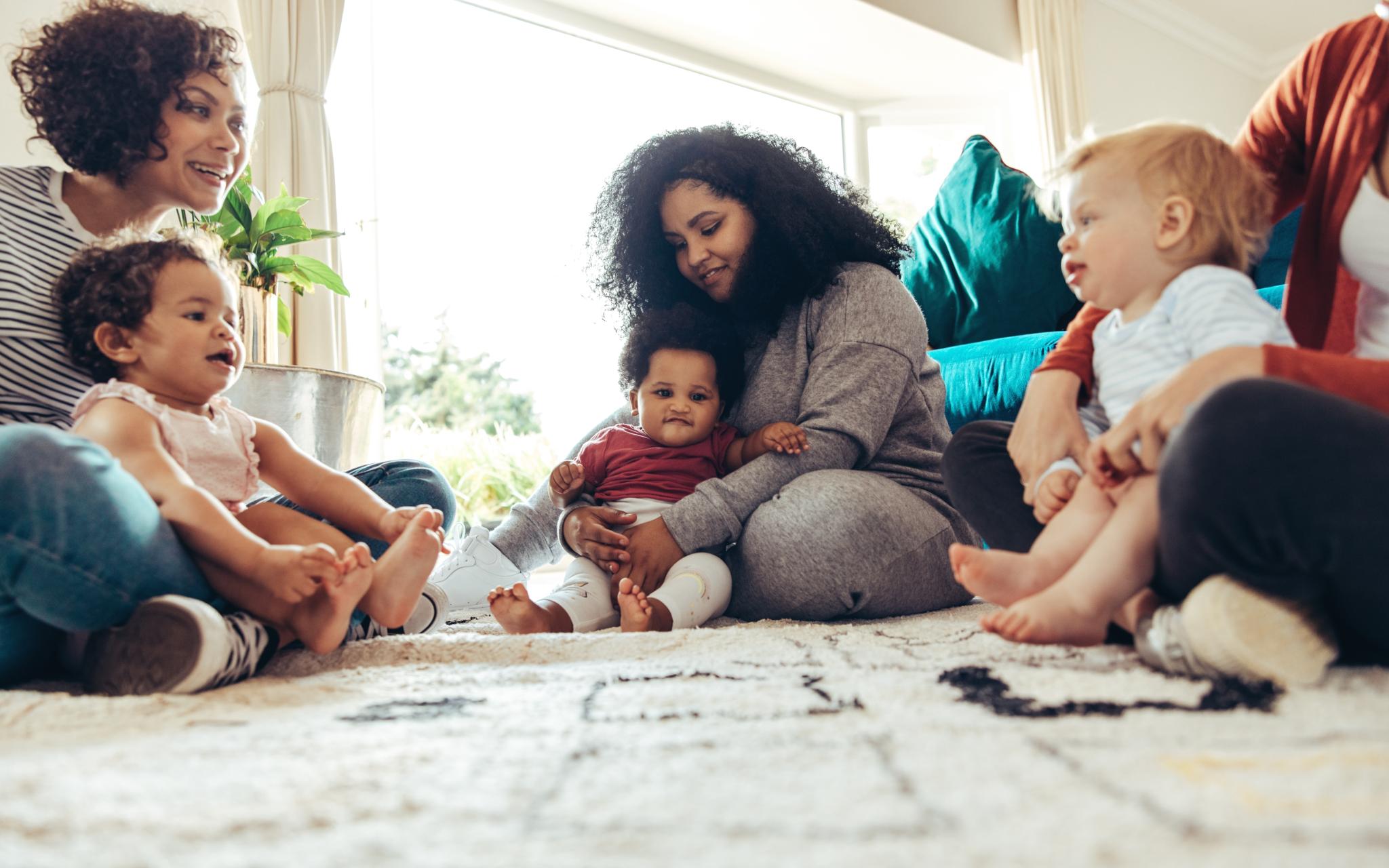 Mehrere Frauen sitzen zusammen mit ihren Kindern auf dem Boden
